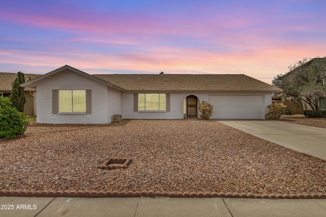 ranch-style home featuring driveway, a garage, brick siding, and a shingled roof