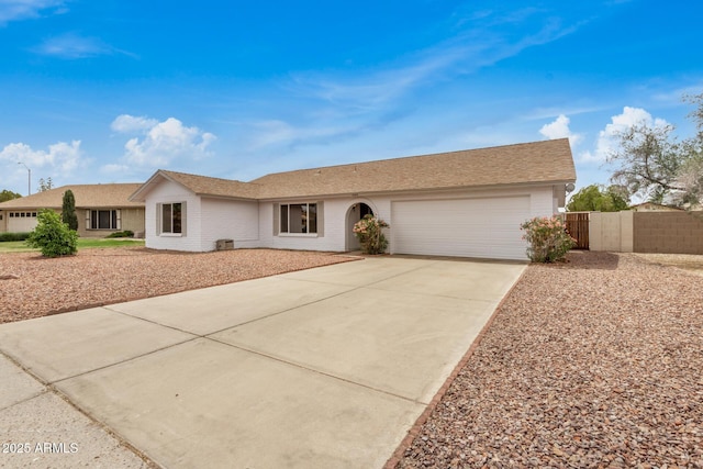 ranch-style home with a garage, driveway, fence, and brick siding