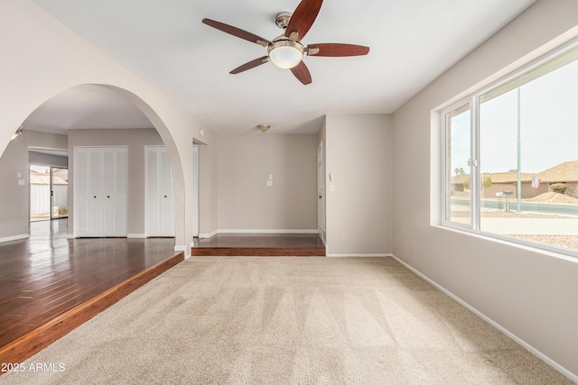 unfurnished room featuring plenty of natural light, a ceiling fan, baseboards, and carpet flooring
