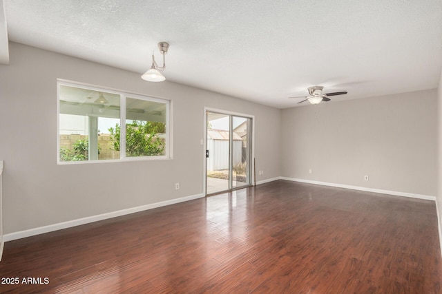 spare room featuring ceiling fan, baseboards, dark wood finished floors, and a textured ceiling