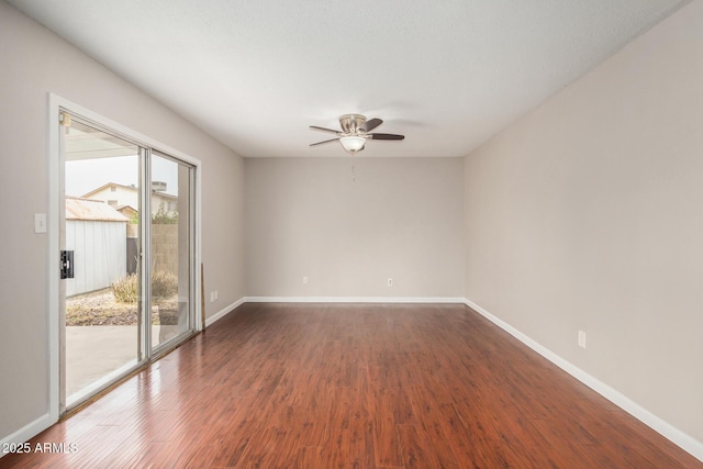spare room with a ceiling fan, dark wood-style floors, and baseboards