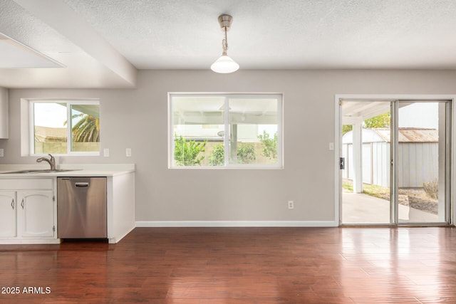 kitchen with stainless steel dishwasher, a sink, baseboards, light countertops, and a textured ceiling