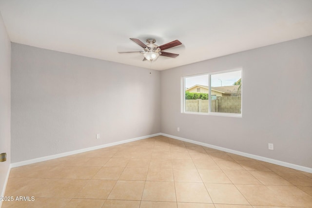 spare room featuring a ceiling fan and baseboards
