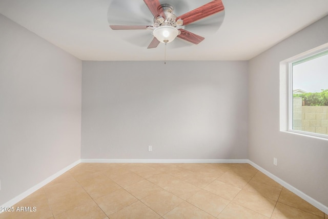 empty room featuring ceiling fan, light tile patterned floors, and baseboards