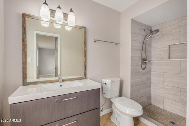 bathroom featuring tiled shower, toilet, vanity, tile patterned floors, and baseboards