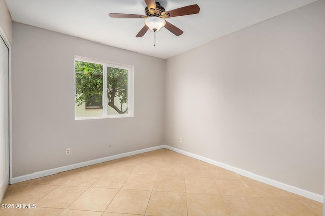 spare room featuring light tile patterned floors, baseboards, and ceiling fan