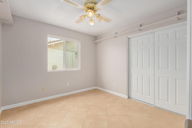 unfurnished bedroom with baseboards, light tile patterned flooring, a closet, and a ceiling fan