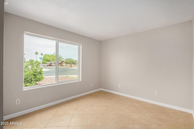spare room featuring healthy amount of natural light, baseboards, and light tile patterned flooring