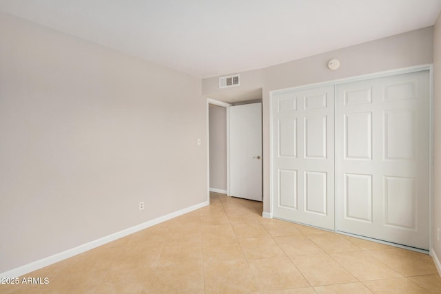 unfurnished bedroom with light tile patterned floors, baseboards, and a closet