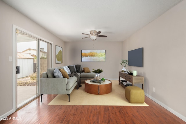 living room featuring a ceiling fan, wood finished floors, and baseboards