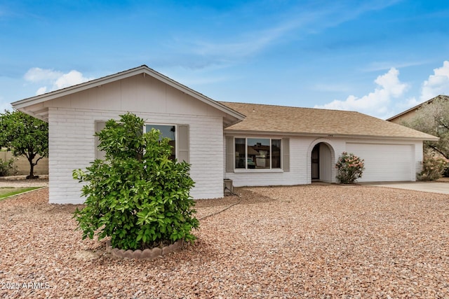 ranch-style home with brick siding, an attached garage, driveway, and a shingled roof