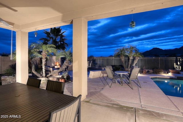 patio terrace at dusk featuring a fenced in pool