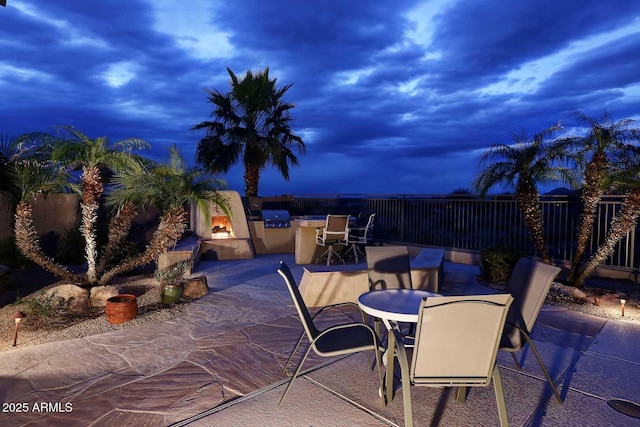 patio terrace at dusk featuring exterior kitchen and grilling area