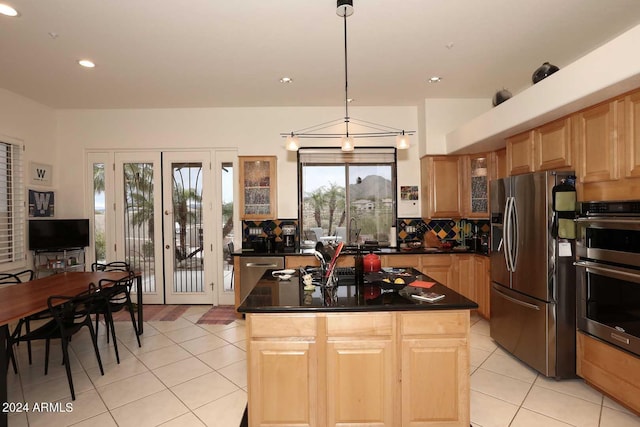 kitchen featuring hanging light fixtures, decorative backsplash, a kitchen island, and appliances with stainless steel finishes