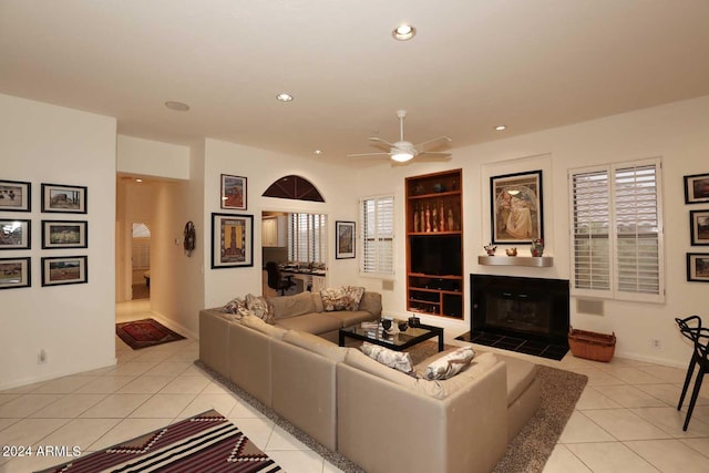 tiled living room featuring ceiling fan and a tiled fireplace