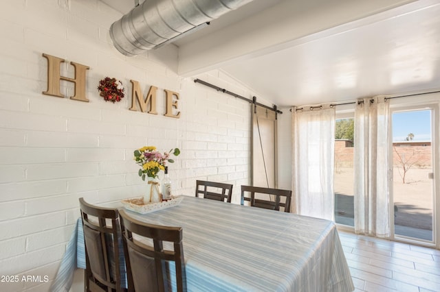 dining area featuring brick wall and a barn door