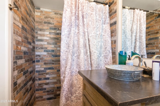 full bathroom featuring brick wall, a sink, and a shower with curtain