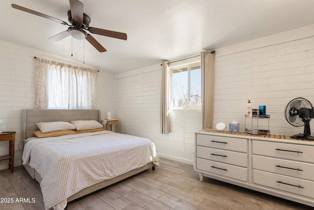 bedroom featuring light wood-style floors, lofted ceiling, multiple windows, and brick wall