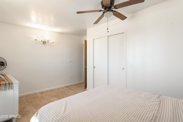 bedroom with a closet, light wood-type flooring, a ceiling fan, and baseboards