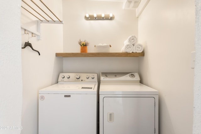 clothes washing area with laundry area, visible vents, and washing machine and clothes dryer