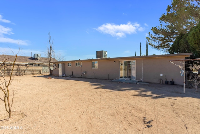 rear view of house featuring fence and central AC unit