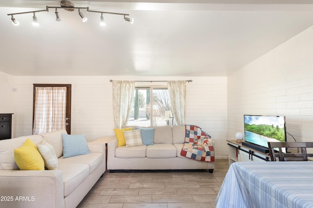 bedroom featuring wood finish floors, vaulted ceiling, and brick wall