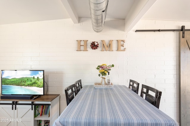 dining room with brick wall, a barn door, and beam ceiling