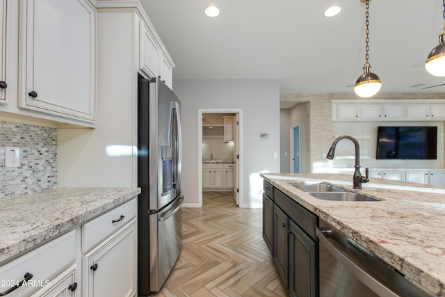 kitchen with sink, hanging light fixtures, light stone counters, white cabinetry, and stainless steel appliances