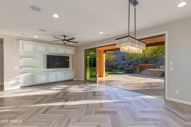 interior space with light parquet floors and ceiling fan with notable chandelier