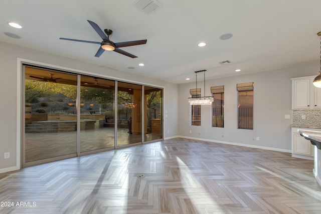 unfurnished living room featuring light parquet flooring, ceiling fan, and a healthy amount of sunlight