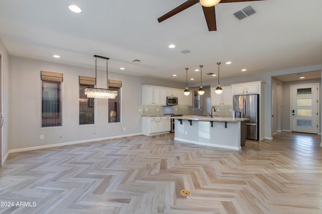 kitchen featuring pendant lighting, decorative backsplash, an island with sink, white cabinetry, and stainless steel appliances