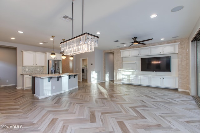 kitchen featuring pendant lighting, a breakfast bar, white cabinets, stainless steel fridge, and a kitchen island