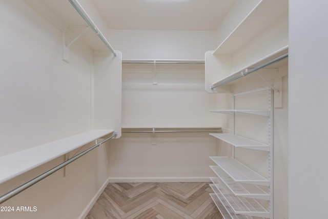 walk in closet with light parquet floors