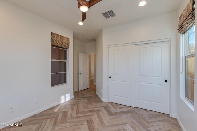 unfurnished bedroom with light parquet flooring, a closet, and ceiling fan