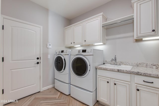 clothes washing area featuring cabinets, light parquet floors, washer and clothes dryer, and sink