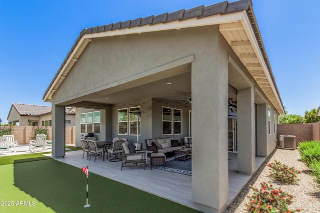 back of property with fence, central AC, stucco siding, an outdoor living space, and a patio