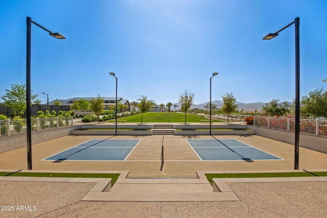 view of tennis court with community basketball court, fence, and a mountain view
