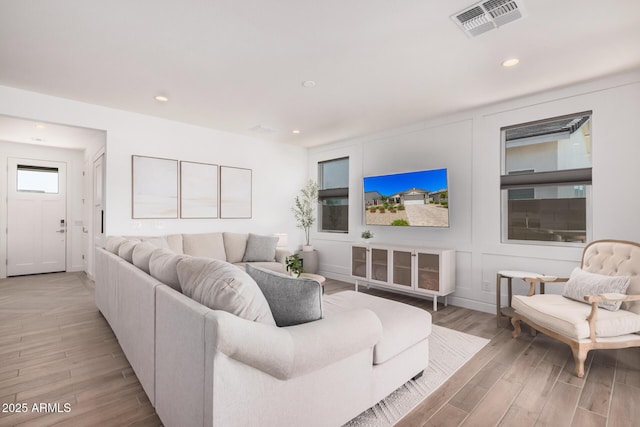 living area featuring recessed lighting, light wood finished floors, and visible vents