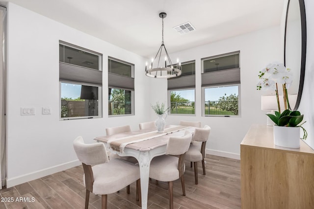 dining space featuring baseboards, visible vents, light wood-type flooring, and a chandelier