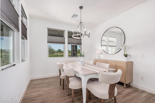dining room featuring an inviting chandelier, baseboards, wood finished floors, and a wealth of natural light