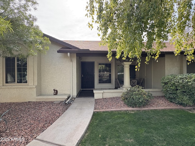 property entrance with covered porch and a lawn