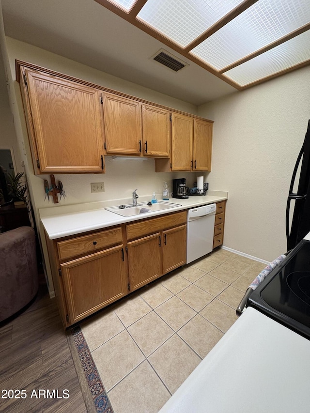 kitchen with light tile patterned flooring, sink, black refrigerator, white dishwasher, and electric stove