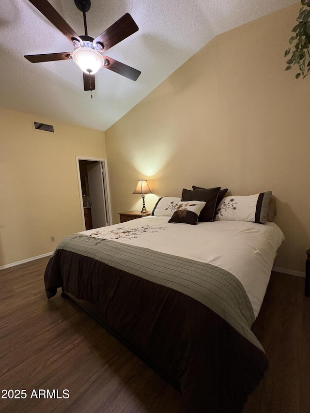 bedroom with dark hardwood / wood-style flooring, ceiling fan, vaulted ceiling, and a textured ceiling