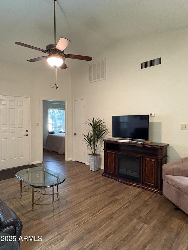 living room featuring dark wood-type flooring, ceiling fan, and vaulted ceiling