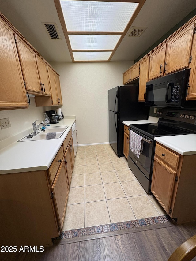 kitchen featuring light tile patterned flooring, sink, and black appliances