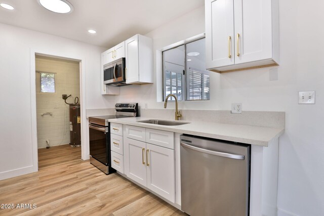 5510 E Dallas St, Mesa, AZ 85205 - kitchen with appliances with stainless steel finishes, a sink, water heater, light wood finished floors, and white cabinetry