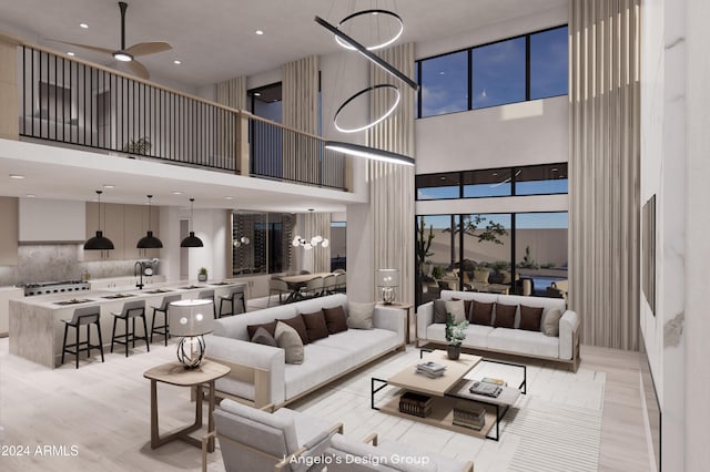 living room with ceiling fan with notable chandelier, light hardwood / wood-style floors, and a high ceiling