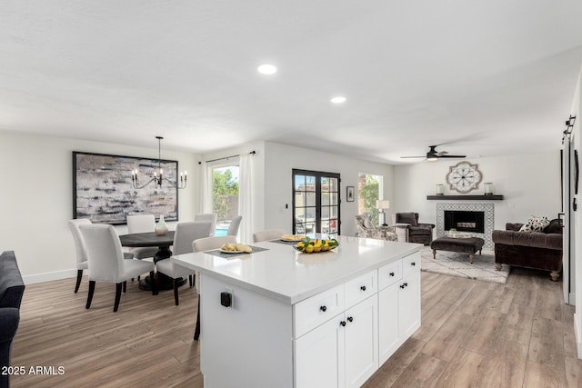5211 E Winchcomb Dr, Scottsdale, AZ 85254 - kitchen with light wood-type flooring, a center island, light countertops, a tiled fireplace, and plenty of natural light