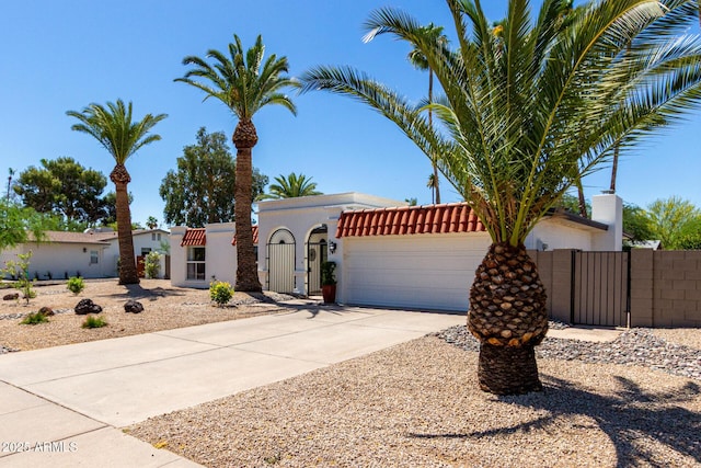 5211 E Winchcomb Dr, Scottsdale, AZ 85254 - mediterranean / spanish home featuring a gate, an attached garage, concrete driveway, and stucco siding