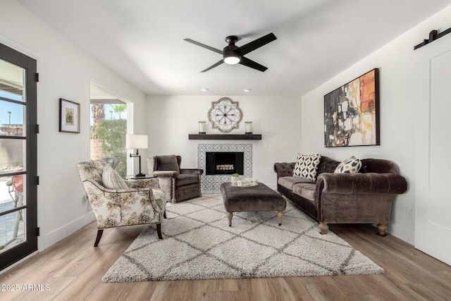5211 E Winchcomb Dr, Scottsdale, AZ 85254 - living room featuring wood finished floors, a tiled fireplace, and a ceiling fan